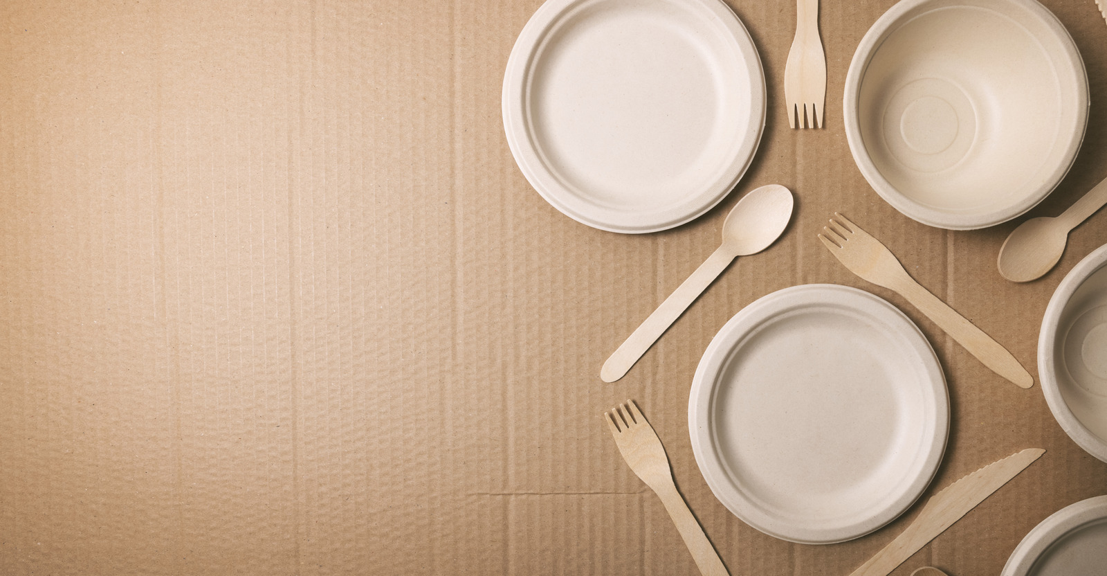 Bamboo tableware and wooden cutlery on cardboard background