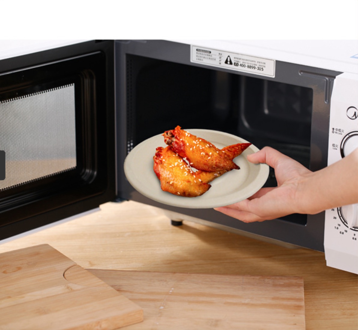 Person placing bamboo plate with chicken wings in microwave, showcasing microwave-safe feature